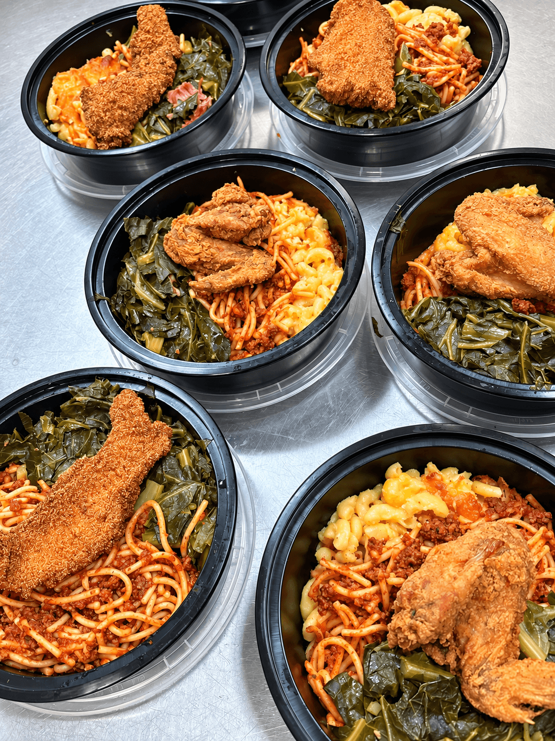 Prepared Kings Kitchen and Cocktails meal bowls with fried fish, macaroni and cheese, spaghetti, and greens