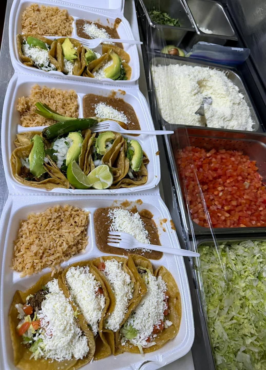 La Tapatia taco plates with rice, beans, avocado, onion, cilantro, cheese, and lime