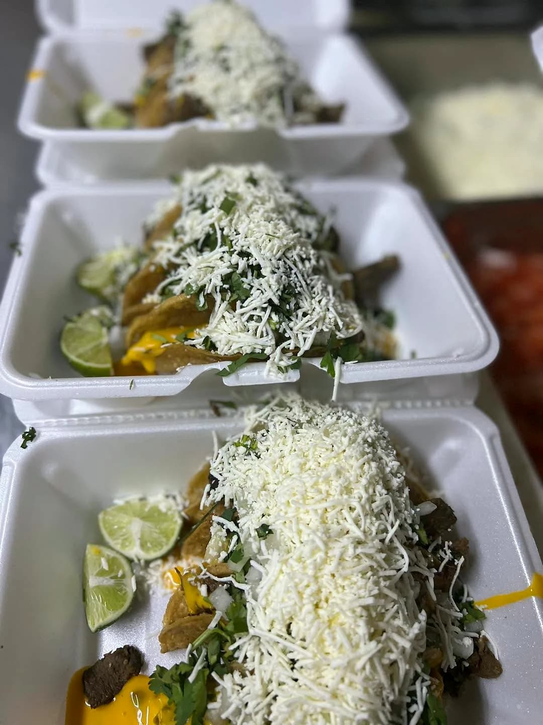 Three La Tapatia taco orders topped with cheese and cilantro with lime wedges