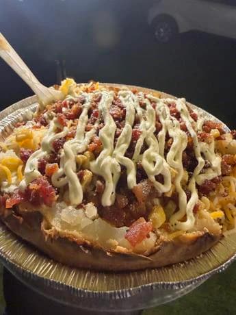 Loaded potato from The Corn King topped with cheese, bacon, and sauce
